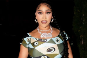 Rapper & Reality TV Star Natalie Nunn Rocks Emilio Pucci Occhi-Print Off-The-Shoulder Fitted Jumpsuit In NYC, Paired With Silver Chanel Mini Hobo Purse ($9,000), Giuseppe Zanotti New Cruel 105 Silver Heels, & New Baddie Records Platinum $150,000 Necklace